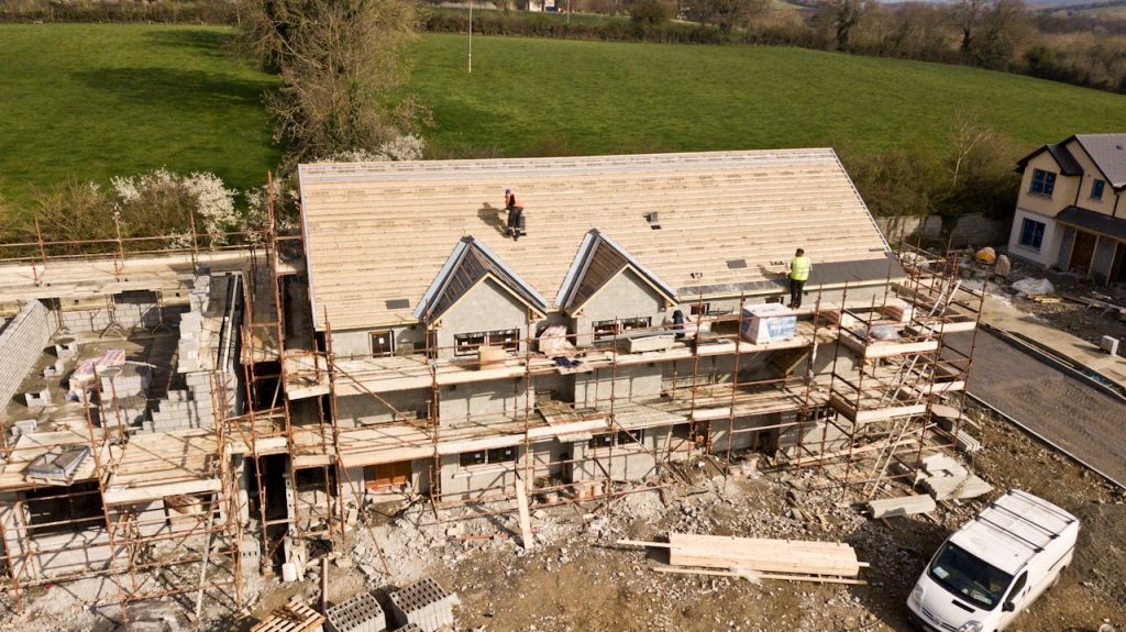 pexels-photo-2098624 Aerial shot of a house under construction in Clonmel, Ireland. Workers on the roof.